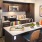 a kitchen with an island and chairs and a fridge and stovetop