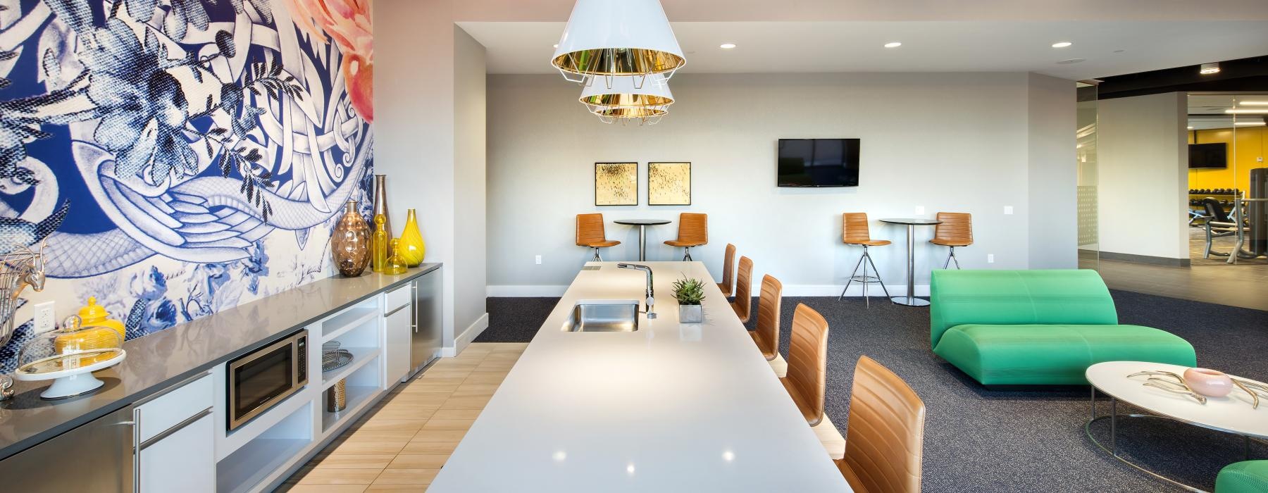 a common room with a large table and chairs and a large painting on the wall