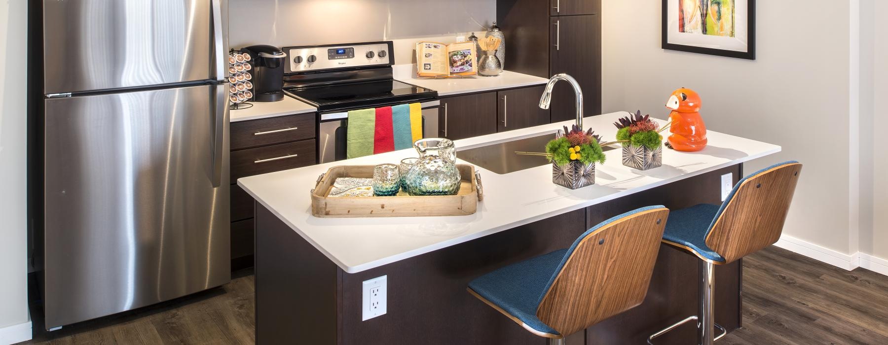 a kitchen with an island and chairs and a fridge and stovetop